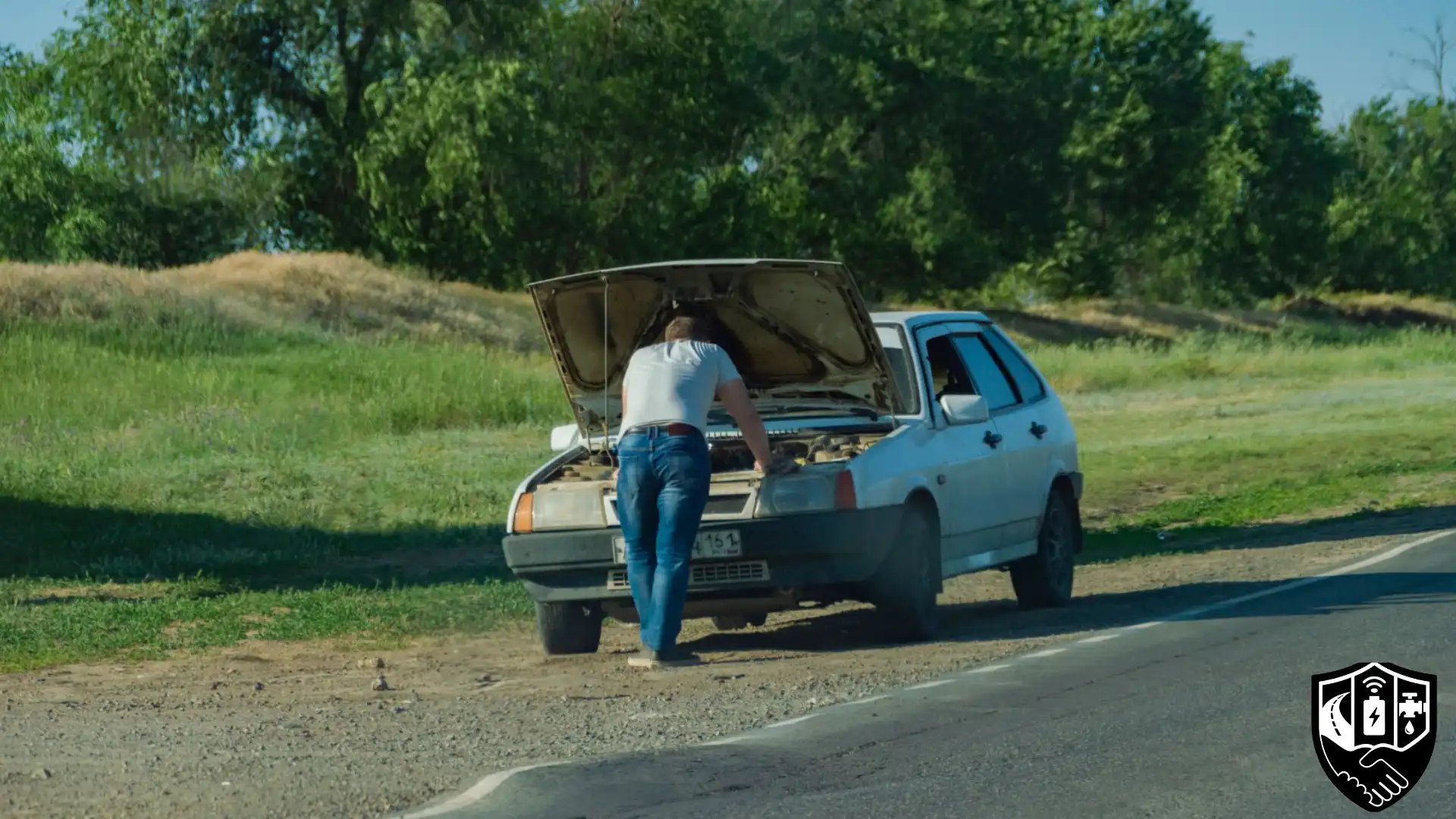 Car-breakdown-safety-highway-optimized A woman standing safely beside her car on the side of a highway with hazard lights flashing, looking calm and in control during a roadside breakdown. A man standing safely on a roadside and checking his car on the side of a highway with hazard lights flashing,
